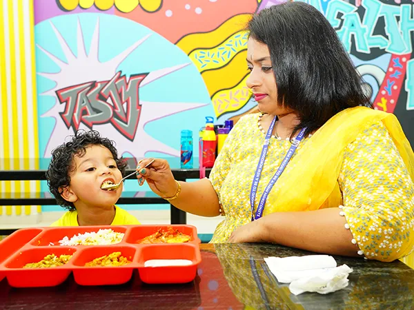 A caregiver helping a young child at lunch