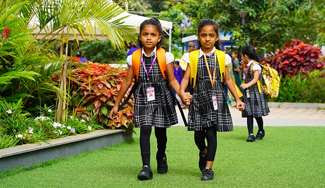 Young learners walking hand in hand into school